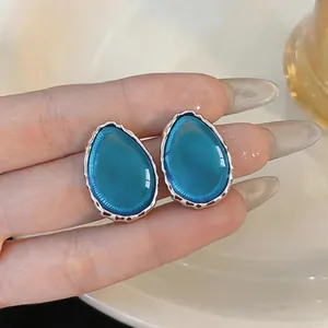 Dettaglio ravvicinato di orecchini a goccia in resina blu vibrante con bordi argento