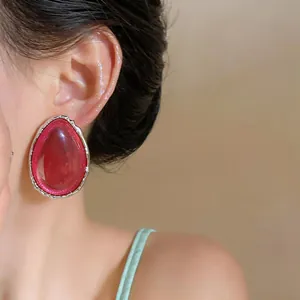Primo piano di un orecchino a goccia in resina rossa con bordo argentato