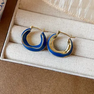 Close-up of 14k gold plated irregular hoop earrings with blue enamel detail