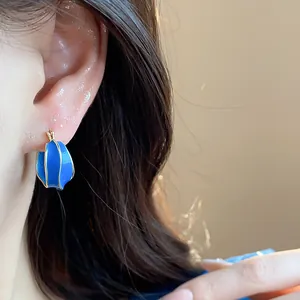 Detailed close-up of 14k gold plated blue enamel irregular hoop earrings on a model's ear