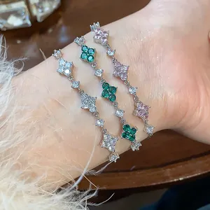 Close-up of three dainty zircon flower bracelets in silver, green, and pink on a wrist.