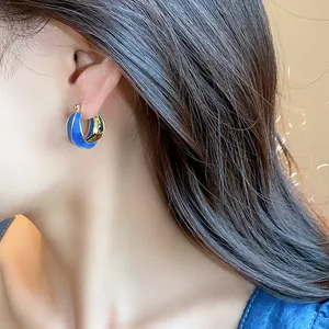 Detailed close-up of 14k gold plated blue enamel irregular hoop earrings on a model
