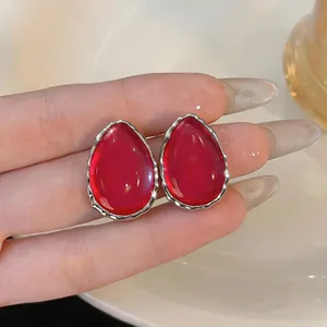 Primo piano di orecchini a goccia in resina rossa con bordo argentato lucido