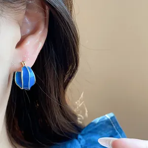 Close-up of irregular blue enamel ear cuff earring with 14k gold plating on model's ear