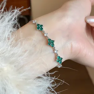 Close-up view of an elegant silver floral bracelet featuring green and white zircons on a wrist