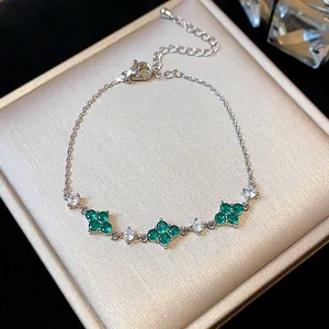 Detailed close-up showing green flower zircons on a delicate silver-plated chain bracelet