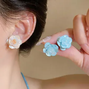 Close-up of elegant camellia flower stud earrings in white and blue shades