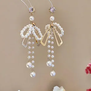Gros plan d'élégantes boucles d'oreilles nœud en perles avec strass violets et pompons