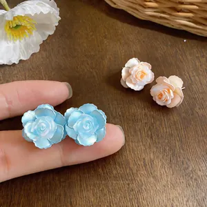 Detailed view of delicate light blue and pink resin camellia flower stud earrings for women