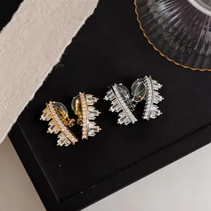 Detailed macro view of sparkling geometric zircon ear clips in gold and silver tones