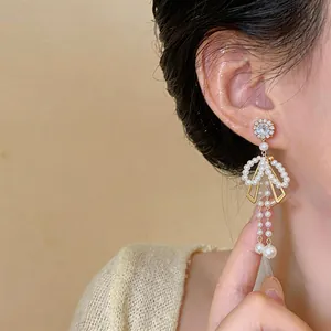 Détail montrant les élégantes boucles d'oreilles nœud en perles avec strass brillants