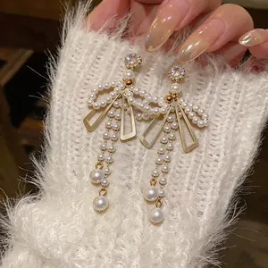 Gros plan de boucles d'oreilles élégantes en perles à nœud avec de longues pampilles et cristaux