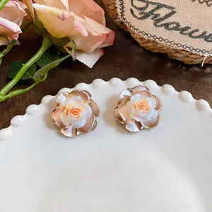 Detailed view of warm-toned camellia stud earrings on a decorative white plate