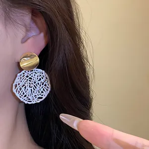 Detailansicht von vintage gold- und weiß hohlen Mesh-Anhänger-Ohrringen an einem Modell