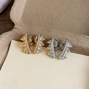 Close-up of sparkling geometric cubic zirconia ear clips in gold and silver finish