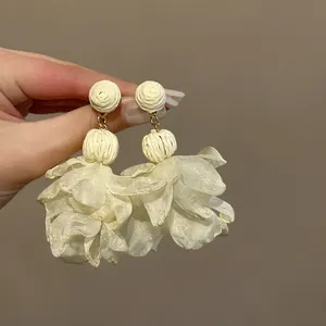 Nahaufnahme eleganter weißer Mesh-Blumenquastenohrringe, perfekt für den Strandurlaub