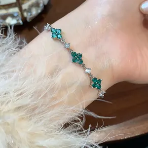 Macro view of an elegant silver bracelet featuring vibrant green zircon flower charms