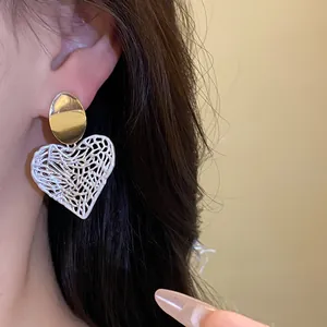 Nahaufnahme von hohlen Vintage-Herz-Ohrhängern am Ohr des Models mit eleganter Silbernadel