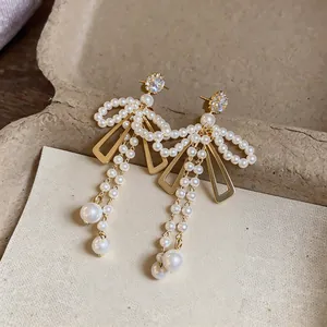 Vue détaillée de boucles d'oreilles nœud élégantes avec perles et strass scintillants