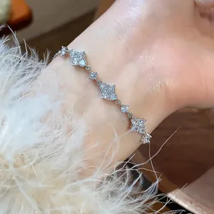 Close-up of a delicate silver bracelet with sparkling zirconia flower charms on wrist.