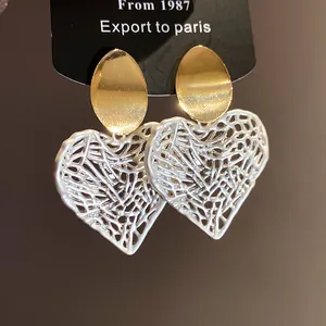Elegante Herz-Ohrringe mit goldenem Stecker und silberfarbenem hohlraum-design im Detail