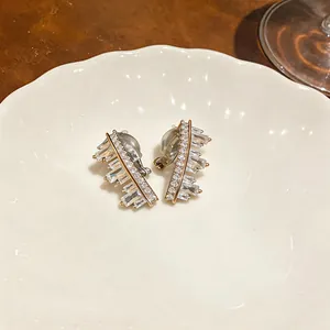 Detailed view of shiny zircon geometric irregular clip-on earrings on a ceramic plate