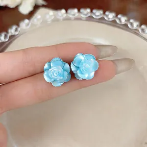 Close-up view of elegant light blue camellia flower stud earrings with delicate layered petals