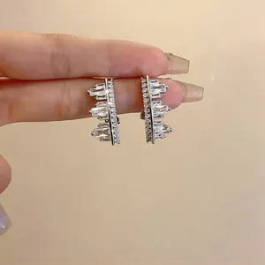 Detail of sparkly zircon geometric irregular clip-on earrings held between fingers