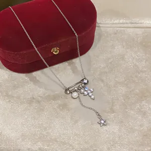 Dettaglio della collana d'argento con spilla, croce di zircone, perla e stella.