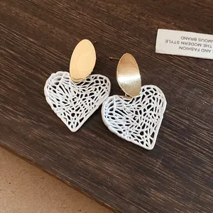 Detailansicht der herzförmigen hohlen Ohrringe mit goldenen Steckern auf Holz