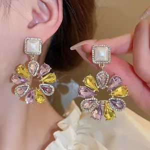 Macro detail of colorful crystal flower earrings with purple and yellow teardrop stones