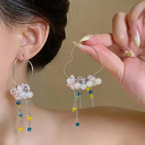 Close-up of sweet heart-shaped earrings with pearls and colorful bead tassels
