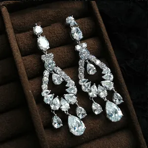 Detailed view of sparkling cubic zirconia teardrop tassel earrings on a brown velvet tray