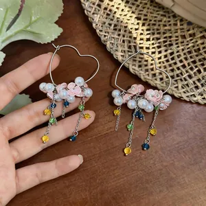 Close-up detail of heart-shaped hoop earrings with elegant pearl and floral tassels.