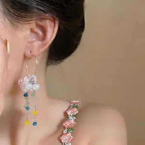 Close-up of sweet heart-shaped earrings featuring pink flowers and colorful bead tassels.