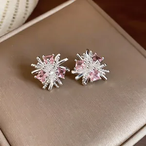 Primo piano di orecchini a lobo a forma di fuoco d'artificio con pietre rosa e finitura argento.