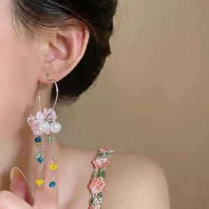 Detail view of sweet floral tassel earring with pearls and colorful beads on model