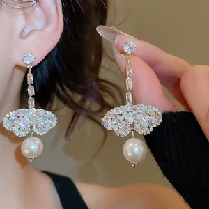Close-up of sparkling zircon butterfly earrings with elegant white pearl drops for women