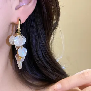 Gros plan de boucles d'oreilles élégantes en glands de coquillage blanc plaquées or 18 carats.