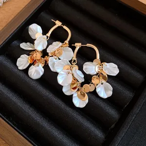 Gros plan détaillé de boucles d'oreilles pompons pétales de nacre dorées dans leur coffret