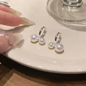 Detailaufnahme von silbernen Perlenohrringen auf einem weißen Keramikteller.