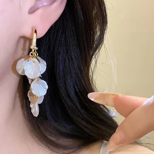 Gros plan de boucles d'oreilles en pétales de nacre dorées portées à l'oreille