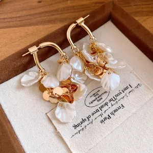 Gros plan sur d'élégantes boucles d'oreilles à pampilles en nacre plaquées or.