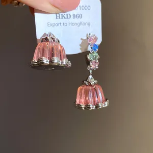 Close-up shot of creative asymmetrical zircon resin pudding drop earrings on a display tag