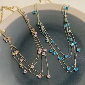 Detailed close-up of multi-layer zircon necklaces in pink and blue on a textured ceramic plate.