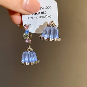 Detailed view of dainty asymmetric blue resin pudding earrings with zircon accents.