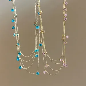 Detail view of a multi-layered gold necklace with colorful blue and pink zircon stones.