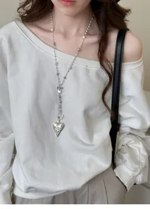 French vintage long pearl necklace with intricate heart pendant worn on white top