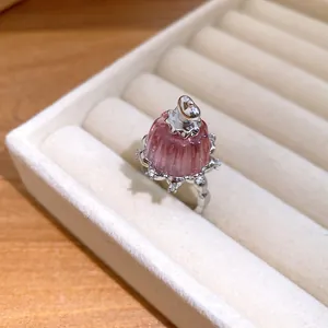Close-up of a delicate pink resin pudding ring with zircon accents in a beige jewelry box slot