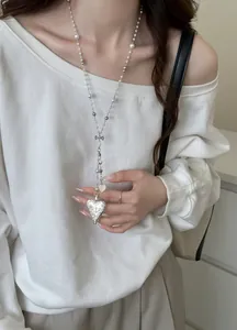 Detail shot of French style pearl heart long necklace with vintage locket on model
